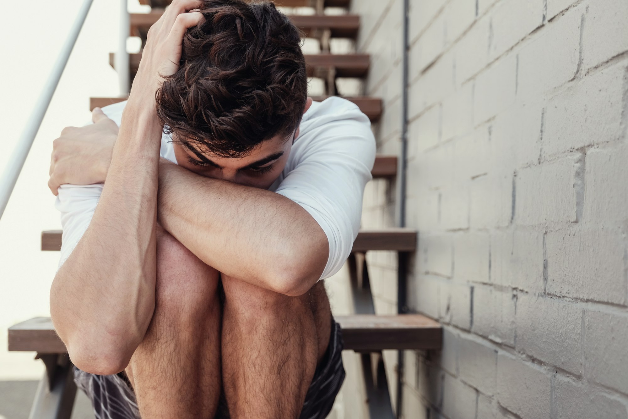 Depressed young adult man sitting alone, mental health concept